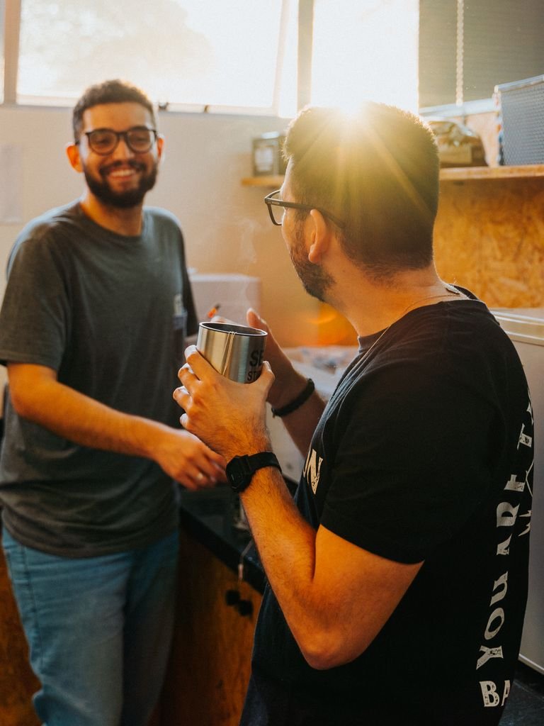 Two men in a kitchen enjoying coffee and bonding under warm sunlight.